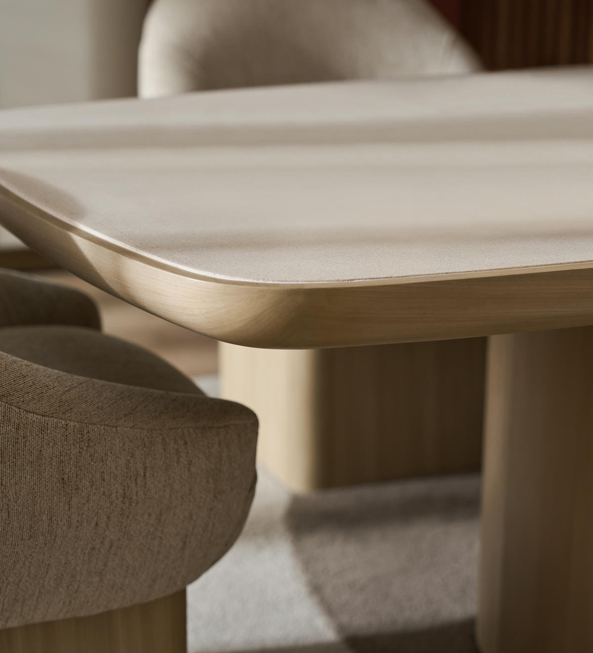 Close-up of a modern dining table with rounded edges and upholstered chair